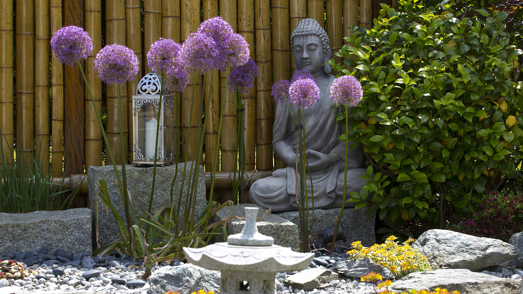 Japanischer Kiesgarten mit Buddahstatue, Steinlaterne und Zierlauch