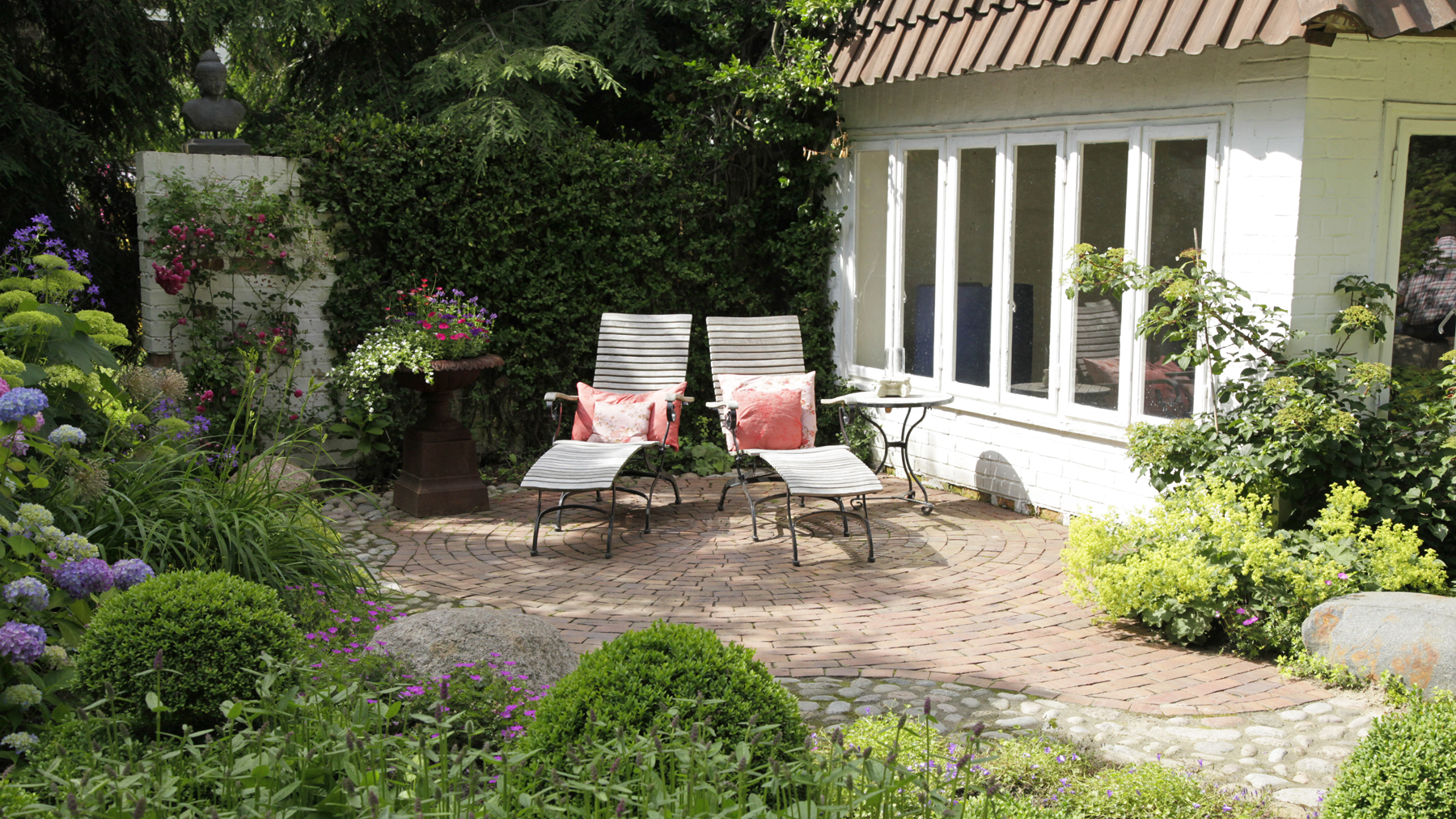 Schattiger Terrassenplatz mit Liegen und Bepflanzung am Gartenhaus